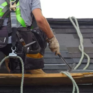 Tittle Brothers Roofing permit contractor on roof with safety harness and hammer