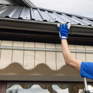 Close-up of a worker's hand installing a gutter on a metal roof