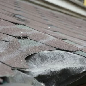 Closeup of aging and damaged asphalt roof shingles, indicating the need for roof replacement