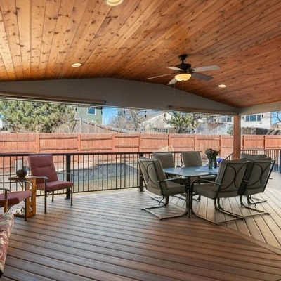 covered-deck-wood-ceiling-outdoor-dining Covered deck with natural wood plank ceiling, ceiling fan, and outdoor dining furniture overlooking fenced backyard