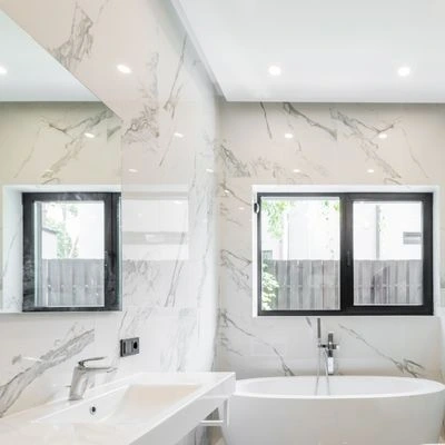 Luxury bathroom with marble walls, freestanding tub, and large window
